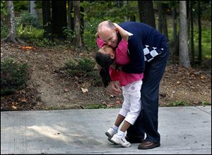 Jim Dotson hugs his daughter, Aselya Dotson, 7, outside their home. Pfizer, for whom Mr. Dotson worked, fired Mr. Dotson days after he adopted Aselya.