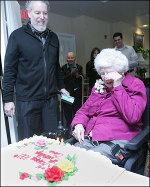 Clara Weinblatt becomes emotional as her son, Chuck, left, and residents of Kingston Care Center of Sylvania sing 'Happy Birthday' to celebrate her 100th. She and her late husband, Dr. Morris Weinblatt, moved to Toledo 60 years ago.