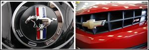 In this combo made from file photos, the logo is shown on the back of a Ford Mustang at a dealership in Wexford, Pa., left, and a 2010 Chevy Camaro RS is shown on display at a dealership in Williamsville, N.Y. Ford is cranking up the horsepower on the 2011 Mustang as it tries to win back muscle car sales from its archrival, the Chevrolet Camaro. (AP File Photos)