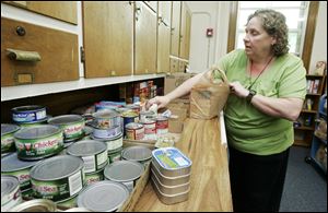 Deb Johnson bags food at the Assumption Outreach Center, which provides food, toiletries, and assistance at the former St. Mary's Church on Page Street.