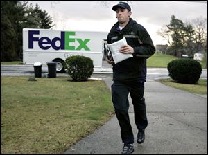 Driver Dan Peake jogs up a driveway of a Rossford home to deliver a package. While the holidays can be hectic and mean long hours, Mr. Peake says he ‘enjoy[s] the spirit of it.'