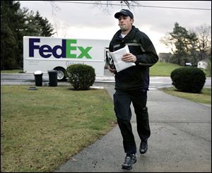 Driver Dan Peake jogs up a driveway of a Rossford home to deliver a package. While the holidays can be hectic and mean long hours, Mr. Peake says he ‘enjoy[s] the spirit of it.'