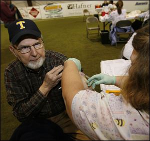 Alan Hogan of Sylvania receives an H1N1 vaccination from Mary Green, a licensed practical nurse from Wauseon. The clinic yesterday at Maumee's Soccer Centre was the first at which the vaccine was offered to anyone in Lucas County not considered high risk for swine flu.