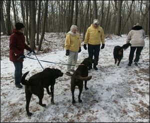 Kristin Wroblewski of Toledo, at left with dogs, stops to talk with Ann and Dick Hamilton as the two volunteers patrol the trails in Wildwood Metropark on Central Avenue in Toledo.
