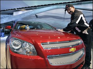 Lupe Castaneda, an auto detailer,
polishes the hood of a  Chevrolet Malibu LTZ as General Motors Co.'s display is readied for the auto show at Cobo Center in downtown Detroit.