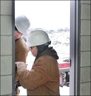 BIZ build10p   Troy Schwartz (cq), of New Brement, left, and Pat Geis, of Botkins, install a door at Navarre Crossings in Oregon, Ohio on January 6, 2010. Pat Geis, construction supervisor, says that they are building a Verizon store on one part of htebuilding, with room for three other businesses. The total area is about 8250 square feet. Geis, of Botkins, who is on site, can be reached at 937.538.0055. Expected completion date is March 2010. Schnippel Construction, of Botkins, Ohio is the company building Navarre Crossings. Their number is 937.693.3831. Need stand-alone construction art for Sunday business section. Get various action shots of workers building a strip center, Navarre Crossings. Try to get phone number for caption info.  Jetta Fraser/Toledo Blade
