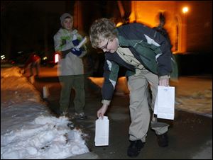 Slug: NBRN luminaria13p Date:  01062010     Andy Morrison       Location: Monroe  Caption: Sean Kazmierski, 12, and other members of Boy Scout Troop 502, place luminarias around Trinity Lutheran Church as residents in the historic Old Village Plat neighborhood light luminarias along the sidewalks to recognize the 12th night or the feast of the Epiphany, Wednesday, 01062009. Summary.