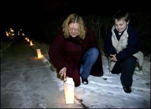 Slug: NBRN luminaria13p Date:  01062010     Andy Morrison       Location: Monroe  Caption: Nanette Frost and her nephew Clint Frost, 10,  light luminarias around her house at 205 E. Third Street as residents in the historic Old Village Plat neighborhood light luminarias along the sidewalks to recognize the 12th night or the feast of the Epiphany, Wednesday, 01062009. Summary.