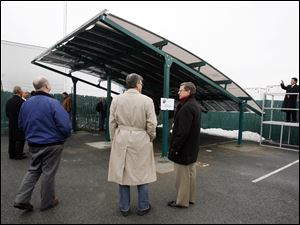 This solar roof on a carport, the first product made by ShadePlex LLC of Toledo, is shown off in a parking area next to the Maumee headquarters of the Lathrop Co. A fabric used with the panels is to improve its electricity generation. ShadePlex hopes to sell the product, which it displayed Friday, to dome and tent makers.