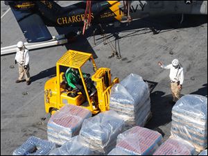 Sailors aboard the aircraft carrier USS Carl Vinson move pallets of relief supplies yesterday as the ship arrives off the coast of Haiti to provide quake aid.