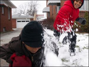 Slug: ROV snowfun            Date 1/16/2010           The Blade/ Amy E. Voigt       Location: Toledo, Ohio  CAPTION:  Christion (CQ O not a) Edwards, left, 6, gets sprayed with snow after his brother Christopher Edwards, 7, right, lobs a snowball at him on the corner of Monroe St. and Sherbrooke Rd. on January 16, 2010.