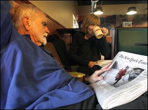 Frank Ayers of Toledo scans a newspaper for details of the crisis in Haiti while Toledoan Heather Meyer listens to a performance during a fund-raiser for  relief efforts for survivors of last week's earthquake in Haiti. Yesterday's event at Caffeini's Coffee, 1471 Secor Rd., included music, poetry readings, and lectures. In addition to donations, Caffeini's contributed part of its proceeds to the Red Cross. Elsewhere, Prestige Restaurant, 3439 Hill Ave., says it will donate a portion of all proceeds from 9 a.m. to 8 p.m. today to the American Red Cross for Haitian relief.