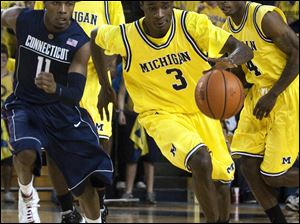 Michigan's Manny Harris streaks up the court while being pursued by Connecticut's Jerome Dyson.