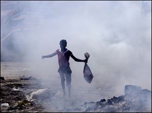 Smoke from fires that are burning unclaimed bodies surrounds a person running in Port-au-Prince, Haiti's capital.