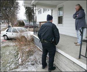 Toledo police officer Craig Smith  talks to Valerie Higgins of Toledo, Ohio, after a police chase ended in front of her home.
