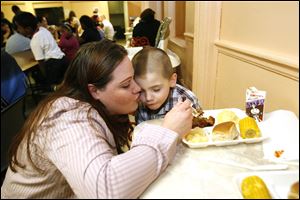 Jennifer Shuff encourages her son, Kaiden Kennedy, to eat at the Family House shelter on Indiana Avenue. She and her husband, Brent Shuff, and their four children are newly homeless.