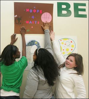 NBR haitihoops29           01/29/2010       The Blade/Lori King  from left; 6th graders Brianna Billings, Bianca Denton and Morella Jansheski put up their sign in support of the Hoops 4 Haiti fundraiser at Bennett Venture Academy in Toledo, OH.