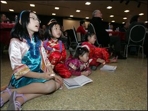 Sunday's event observed the Chinese New Year, the Year of the Tiger. At right, Cherice Chan, 9, left, and Amy Dong, 7, both of Toledo, and Candy Lin, 8, and her sister, Ruthie Lin, 4, both of Perrysburg, are focused on a choral performance at the event. More than 240 people attended.
