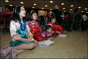 Sunday's event observed the Chinese New Year, the Year of the Tiger. At right, Cherice Chan, 9, left, and Amy Dong, 7, both of Toledo, and Candy Lin, 8, and her sister, Ruthie Lin, 4, both of Perrysburg, are focused on a choral performance at the event. More than 240 people attended.