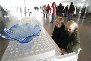 Sam Garner, 9, and his sister Sadie Garner, 7, of Holland, play a glass-covered piano at the Glass Pavilion. WinterFest continues next weekend with special offers and discounts offered.