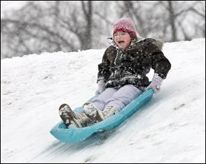 Gabrielle Whitzel, 7, of Toledo finds smooth sledding at Fort Miamis Park in Maumee. Classes were canceled yesterday in many area school districts because of the winter storm.