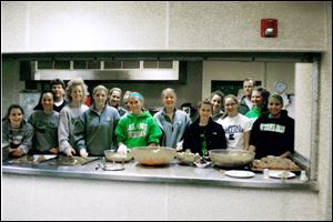 Members of the Ottawa Hills girls basketball team prepare to dish out the meal they prepared at the center.