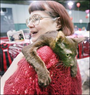 Candice Massey of Alpena, Mich., hugs her Havana Brown cat at the show, which continues Sunday at the rec center in Maumee.