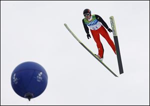 Switzerland's Simon Ammann sails by a balloon en route to winning the first gold medal of the Games.