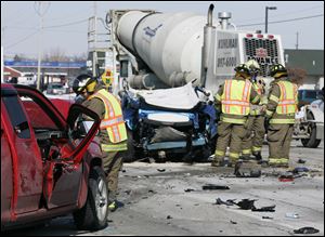 CTY wreck19p   2/19/2010  The Blade/Dave Zapotosky Caption: Firefighter stand bye at the scene of a crash involving a cement mixer, a car, and a pick-up truck on Oregon Rd., south of Route 795, in Perrysburg Township, Ohio, February 19, 2010.  The blue car , center, was stopped in the left lane of the southbound side of Oregon Road, waiting to make a left turn, and was rear ended by the red pick-up truck, left, pushing it into the path of the northbound cement mixer.