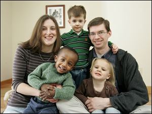 Rachel and Keith Simpson pose in their home in Holland with their children, David, 20 months, who was adopted from Ethiopia; Henry, 4, and Ruth, 3.