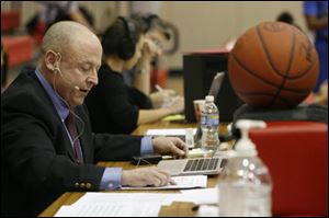 Brian Brown checks his notes while calling a basketball game for the Owens Community College Express. 'I have a passion for this,' the retired teacher said.