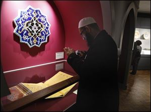 Imam Sohel Mangera photographs a Qur'an from about 1450-60 displayed at the Detroit Institute of Art in Detroit, Wednesday, Feb. 23, 2010. In the heart of the largest concentration of Muslims in the U.S., the Detroit Institute of Arts opens its new permanent gallery of Islamic art. The gallery of about 170 works of art from the Mediterranean region, the Middle East, Central Asia and India opens Sunday.