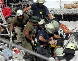 Rescue workers carry a survivor from the ruins of a demolished building in Concepcion, Chile, on Saturday.