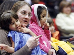 JoAnn Sanchez holds her 3-year-old twins, Joey and Jenna, as they listen to the Libbey jazz ensemble.
