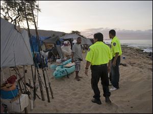 Officers with the Hawaii Department of Emergency Management notify homeless campers on Maile Beach in Waianae, Hawaii, of the tsunami warning.