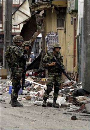 Soldiers stand guard in the streets of Talcahuano, Chile, Sunday, Feb. 28, 2010. A devastating earthquake struck Chile early Saturday Feb. 27, 2010 knocking out power and closing most businesses.