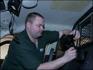 Dennis Ebel works on installing the new system in a city police cruiser. Police officials especially like the backseat camera and recorder, which can capture evidence that suspects might divulge. Installation is expected to be finished by the end of the month.