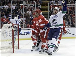 Vancouver's Henrik Sedin celebrates a first-period goal by Alexandre Burrow, left, against Detroit in last night's game.
