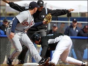 Toronto's Jose Bautista, right, slides safely under the tag of Detroit's Brent Dlugach during the Tigers' spring training opener.