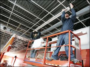 BIZ build07p   3/3/2010  The Blade/Dave Zapotosky Caption: Nick Carson, left, and James Land, of Bash and Associates, Indianapolis, Ind., install a light fixture at the AutoZone store under construction in an existing building at 7229 West Central Ave. in Toledo, Ohio, March 3, 2010.