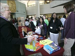 Mary Plews, left, of the Toledo-Lucas County Public Library shares college information with Maya Mitchell, 12, and Sherice Whyte, 12. Washington Local counselor Sara Hoffman is at right.