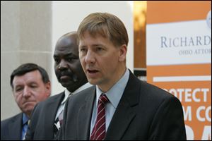 Ohio Attorney General Richard Cordray, foreground, addresses a consumer-protection fair at the main library.  Mayor Mike Bell, center, and Better Business Bureau President Richard Eppstein also spoke.