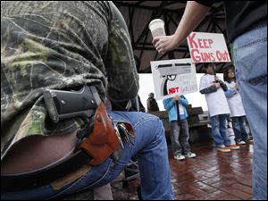 A gun-wearing customer is handed his drink as he observes an anti-gun rally at a Starbucks in Seattle. The chain has reiterated that its policy on weapons is to follow state and local laws.