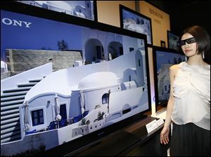Sony Corp's 3-D televisions are introduced as a model watches with 3-D glasses in Tokyo. The company plans to start selling the sets in June, joining an industry push for consumers to buy the sets.