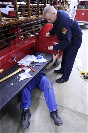 Off-duty firefighter Jamie Ferguson hands a wrench to retired firefighter Frank Dobrosky as he puts a fender on the truck.