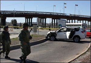 Soldiers stand guard at a crime scene where the crashed car of a US consulate employee sits in Ciudad Juarez, Mexico, Sunday, March 14, 2010. A US consulate employee and her husband were shot to death Saturday in their car, where their baby was found unharmed in the back seat, near the Santa Fe International bridge linking Ciudad Juarez with El Paso, Texas, according to Vladimir Tuexi, a spokesman for Chihuahua state prosecutors' office. 