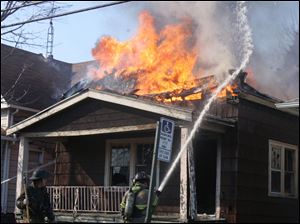 Toledo firefighters contain a blaze in a vacant house at 1606 Hamilton St. near North Detroit Avenue in Toledo and also hosing down a neighboring home that was at risk, below.