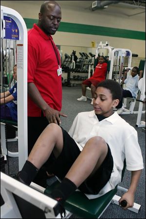 Corey Allison shows TPS student Daquan Jordan, 13, how to use workout equipment at the Wayman D. Palmer Community YMCA on North 14th Street. The initiative includes free transportation for students on TARTA buses from their schools to the partner YMCAs.