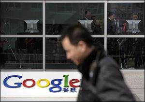 A security guard walks past while foreign visitors are seen inside the Google China headquarters in Beijing Tuesday, March 23, 2010. Google Inc. stopped censoring the Internet for China by shifting its search engine off the mainland Monday but said it will maintain other operations in the country. The maneuver attempts to balance Google's disdain for China's Internet rules with the company's desire to profit from an explosively growing market.