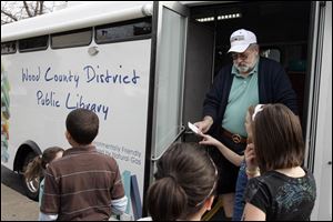 Librarian John Powell assists students during a stop at Eastpointe on the Mall apartments in Northwood.